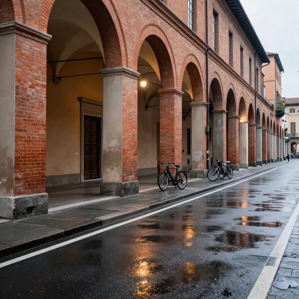 Portico bolognese bagnato al crepuscolo con luce bianca e strada vuota sotto gli archi.